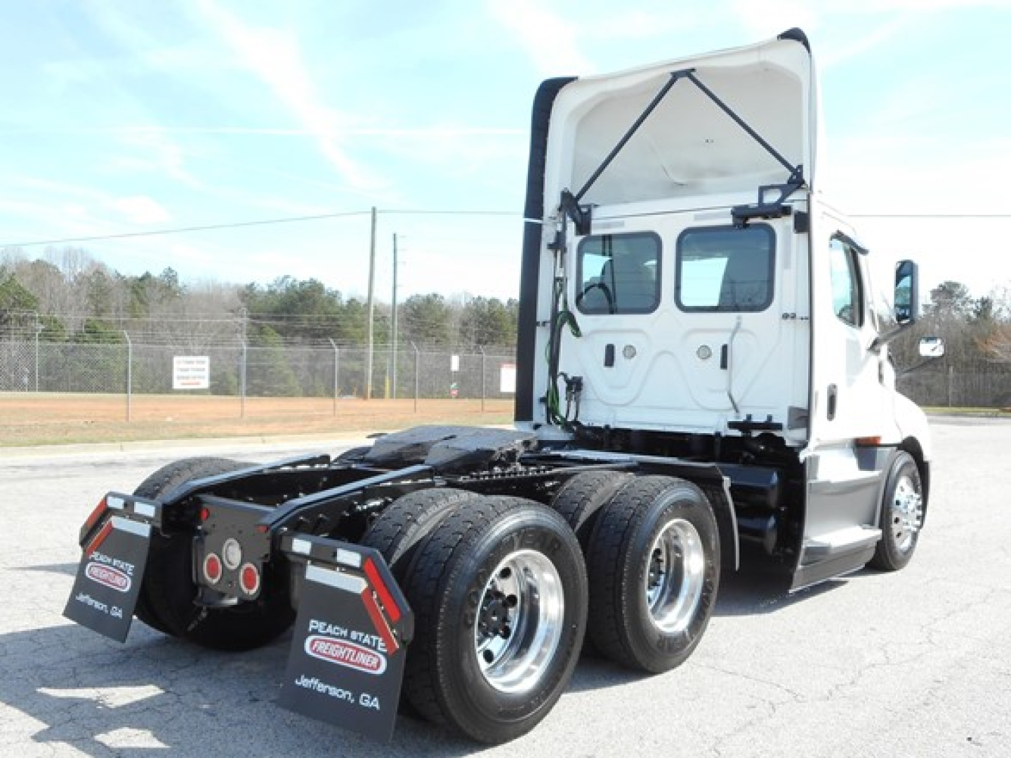 Truck chassis showing rear view with dual rear axles and Freightliner Cascadia 126 cab in white.