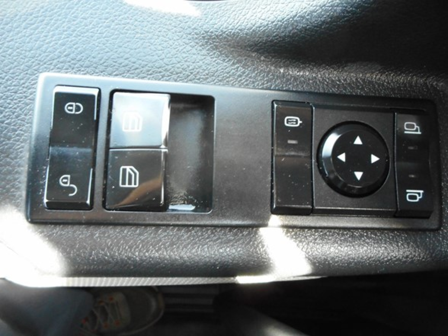 Control panel with window/mirror adjustment switches and round directional pad in a Freightliner Cascadia cab interior.