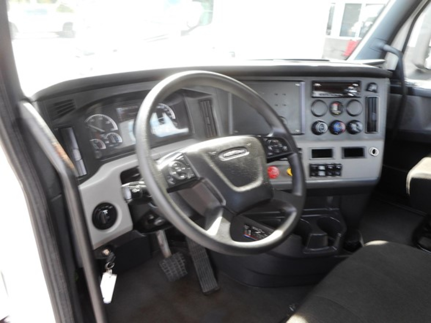 Dashboard and steering wheel of a Freightliner Cascadia truck interior with gauges and controls visible.