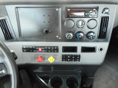 Dashboard panel of a Freightliner Cascadia 126 cabin showing stacked gauges, climate controls, and switches with a blank radio slot.