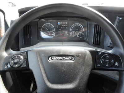 Dashboard and steering wheel of a Freightliner Cascadia day cab showing instrument cluster, steering wheel with Freightliner emblem, and control stalks.