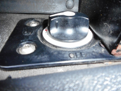 Cap with white ring and surrounding metal plate, three screws, near a black textured surface; appears to be a fill cap with OIL marking.