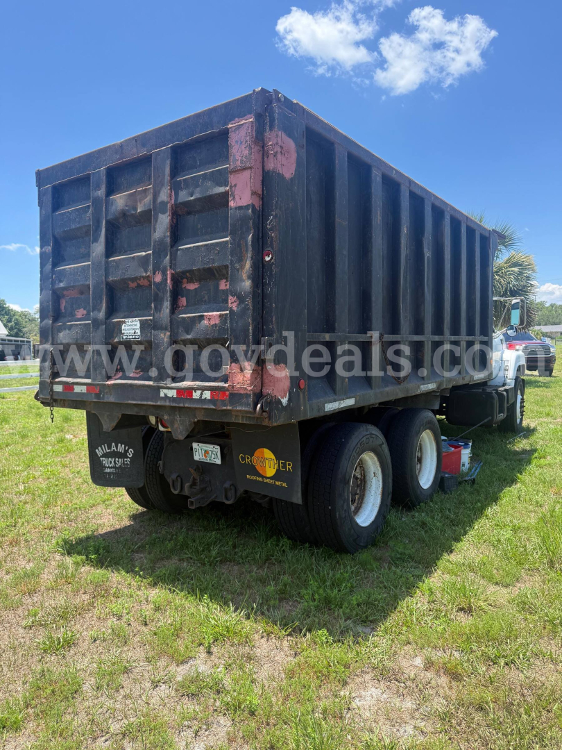Dump bed trailer showing cargo area and rear access doors, GMC dump truck chassis, dual rear wheels, faded dark blue paint with red accents.