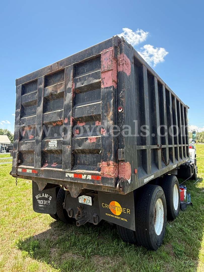 Dump truck rear and side showing black dump bed with pink faded patches and dual rear wheels