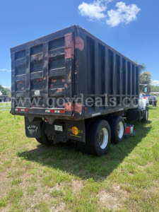 Dump bed trailer showing cargo area and rear access doors, GMC dump truck chassis, dual rear wheels, faded dark blue paint with red accents.