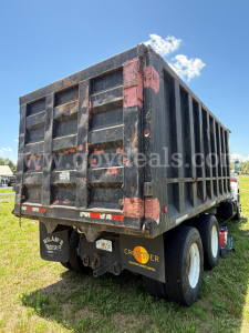 Dump truck rear and side showing black dump bed with pink faded patches and dual rear wheels