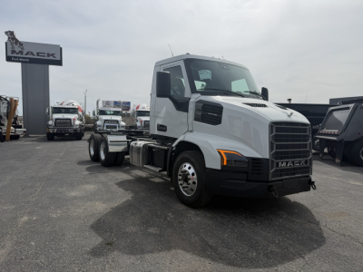2027 Mack AN64T conventional daycab truck in white, front three-quarter view with empty drivetrain chassis, parking lot, Mack sign in background.
