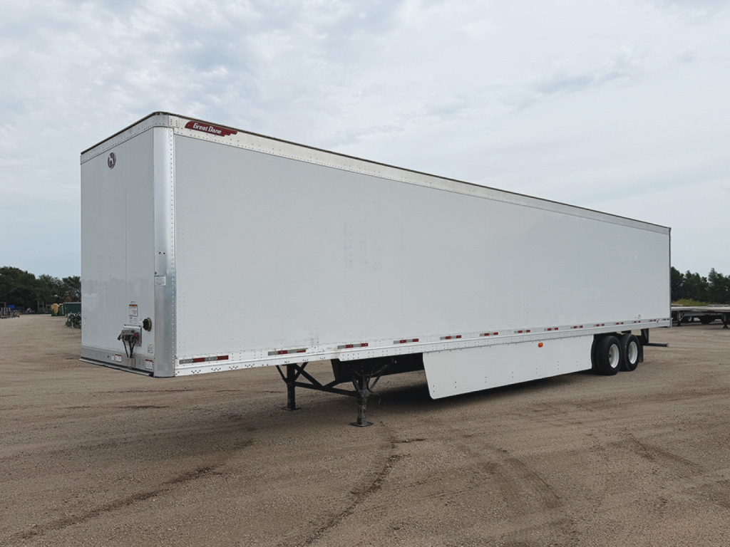 Trailer side view showing a white Great Dane Champion SE trailer with tandem axles and front landing gear.