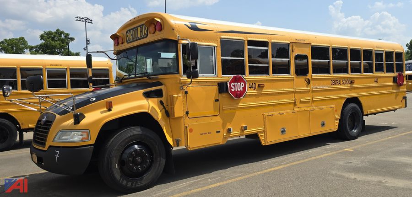 School bus side view showing yellow Blue Bird Vision transit bus with stop sign, doors, and windows; front wheel well and wheel visible.