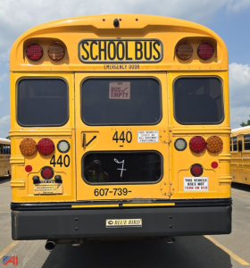Rear view of a 2017 Blue Bird Vision school bus in yellow with emergency door, school bus insignia, and fleet contact number.