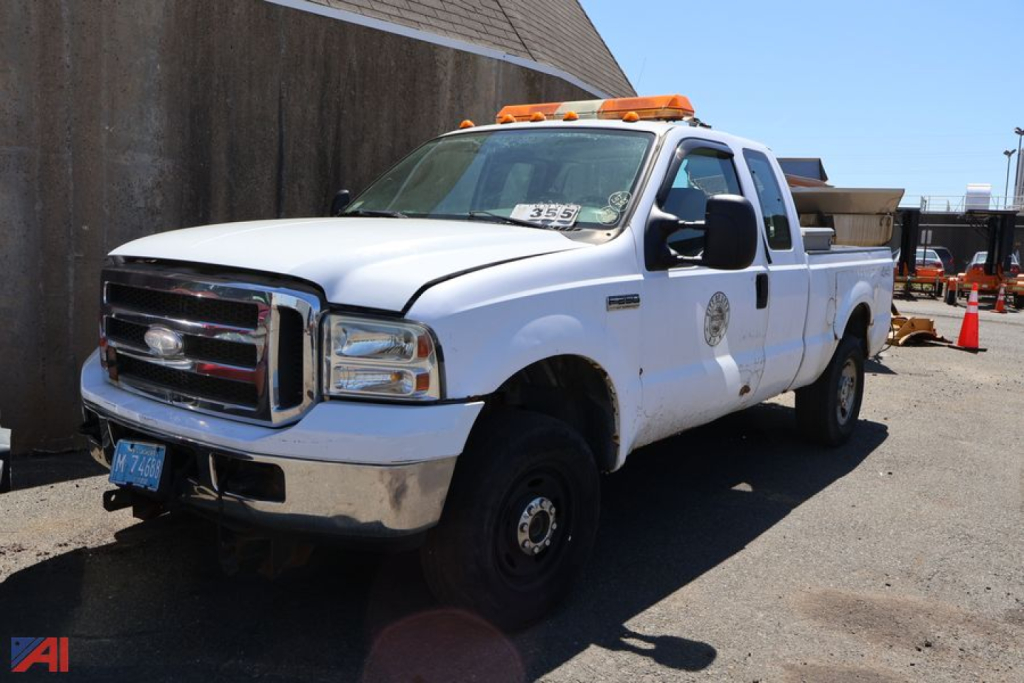 Ford F-250 Super Duty pickup truck white utility body with light bar on cab and company logo on door in a lot