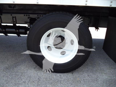 Wheel and tire assembly under Freightliner M2 106 truck with white rim.
