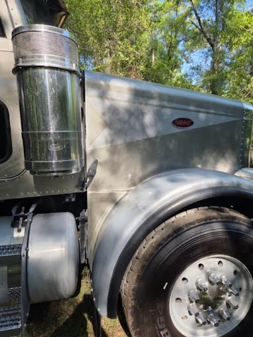 Peterbilt 378 dump truck side showing air intake, front fender, and wheel with chrome hub; Peterbilt emblem on the side of the hood.