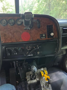 Peterbilt truck cabin dashboard with wood veneer panel, gauges, and a gear shifter in view.