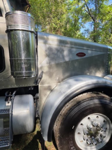 Peterbilt 378 dump truck side showing air intake, front fender, and wheel with chrome hub; Peterbilt emblem on the side of the hood.