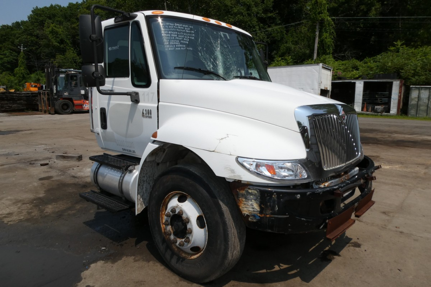 International 4300 beverage truck with white cab and damaged front bumper, side view showing front grille, headlight, and wheel; VIN 1HTMMAAN85H102552 visible on cab window.