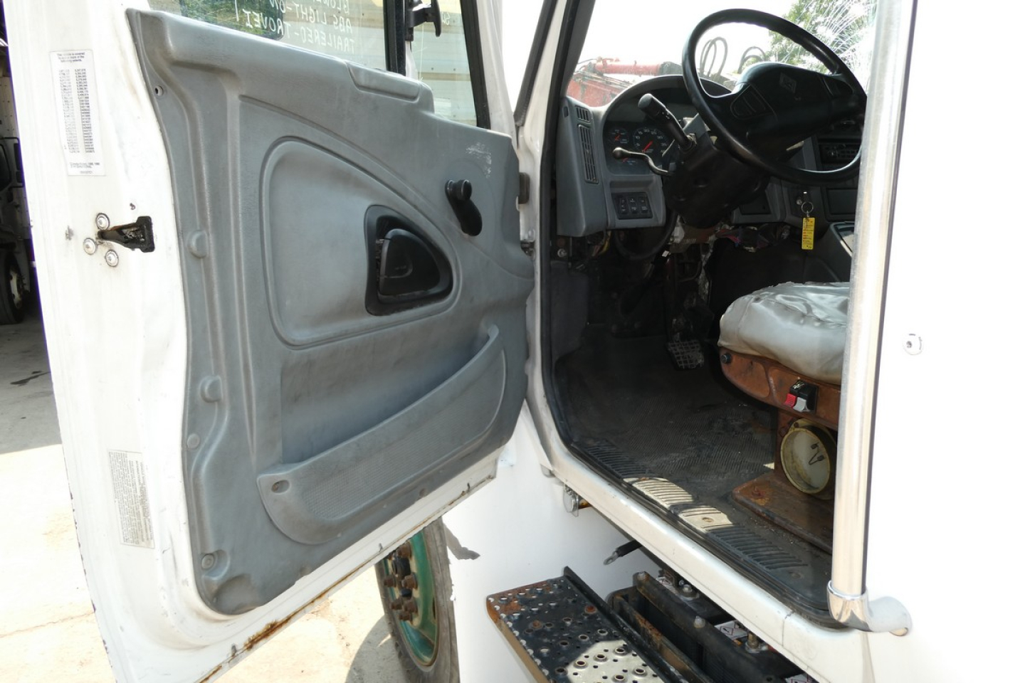 Truck door interior and cabin view of a 2005 International 4300 medium-duty truck showing open door and driver seat area.