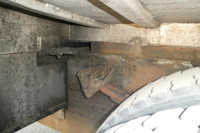Underbody view of a 2005 International 4300 truck showing a wheel, suspension leaf spring, and metal frame with dirt and grease.