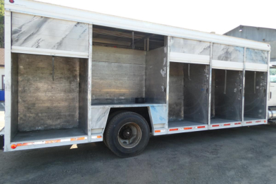 Truck body side view showing an empty aluminum beverage truck trailer with metal walls and open compartments.
