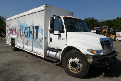 International 4300 box truck in a beverage livery showing front passenger side with damaged bumper and wheel.