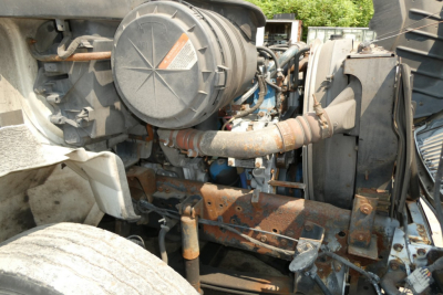 Engine bay of a 2005 International 4300 showing air filter canister, intake piping, radiator area, and rusted support brackets.