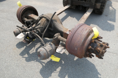 Front axle assembly and drum brakes with wheel hubs for International 4300, showing rusty axles, brake drums, rubber hoses, and suspensions components.