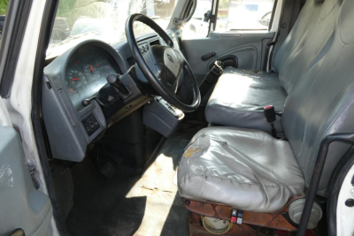 Interior cab of a 2005 International 4300 with worn driver seat and steering wheel, showing dashboard and seating area.