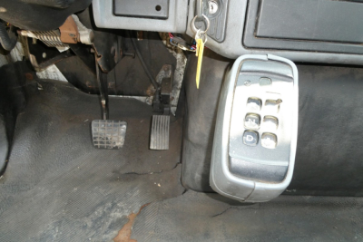 Truck pedal area showing clutch and accelerator pedals with a keypad drive control module mounted to the right under the dashboard, and a set of ignition keys in the ignition switch.