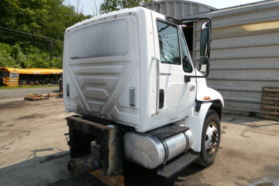 International 4300 dump truck rear/side view showing cab and fuel tanks, white paint, VIN label area, beverage category listing on listing card.
