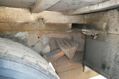 Truck frame area showing suspension/components under a 2005 International 4300 with visible rust and wheel well; includes leaf spring and frame members.