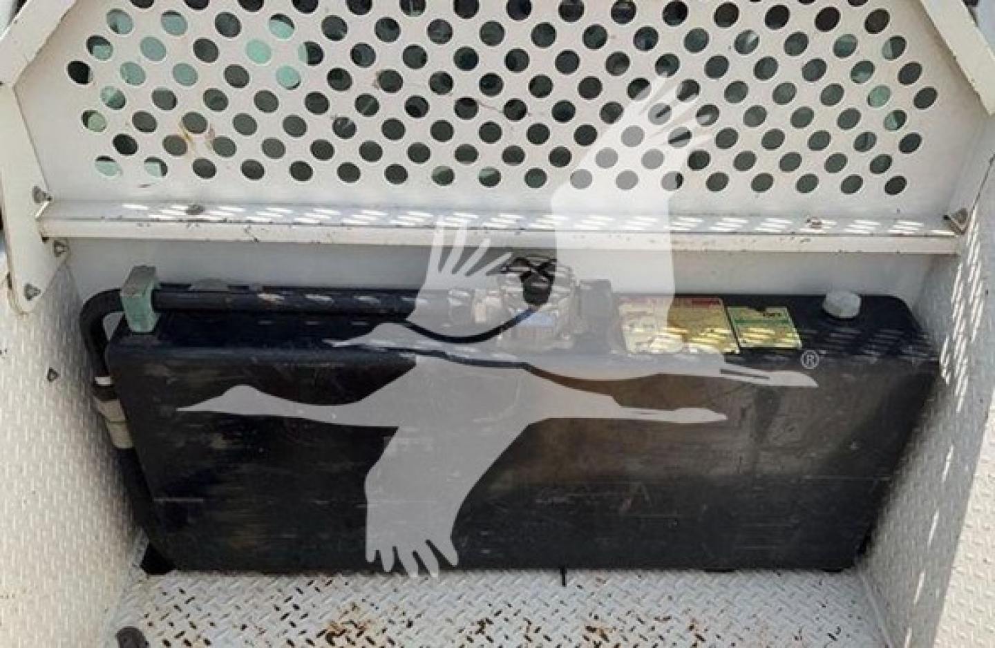 Ford F-550 service truck battery in cargo area with perforated metal divider behind battery.