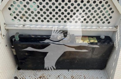 Ford F-550 service truck battery in cargo area with perforated metal divider behind battery.