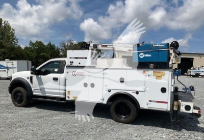 Ford F-550 service utility truck with MilRor Miller equipment on utility bed; various compartments, tool boxes, and a generator unit mounted on the back; white exterior with blue equipment unit.