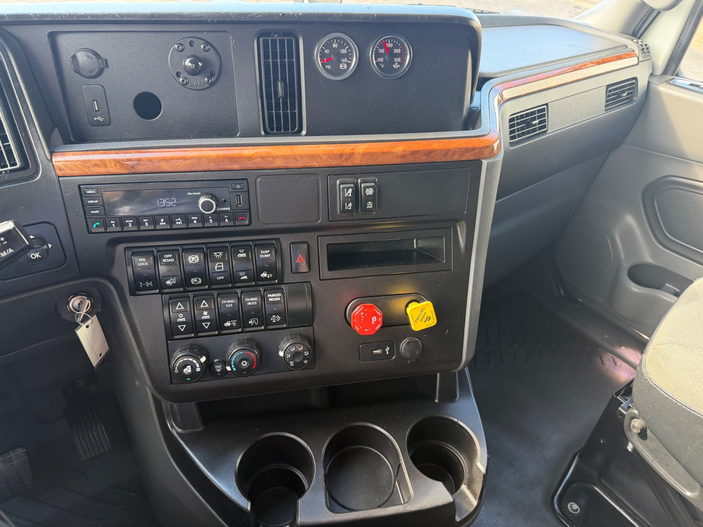 Truck dashboard and center console of a 2021 International LT625 showing instrument cluster, climate controls, and cup holders.