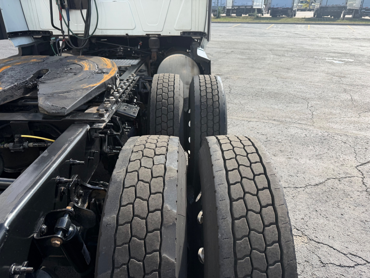 Dual rear axles on a white 2021 International LT625 truck showing exposed chassis and twin tires with tread, part of a sleeper truck configuration.