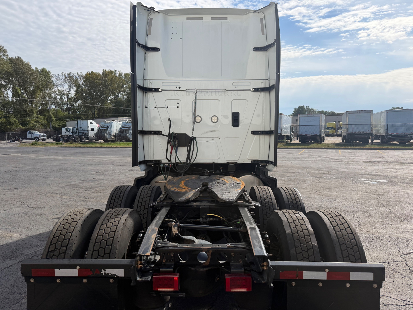 Truck cab rear view showing International LT625 chassis and fifth-wheel area with dual rear axles and spare wheel mounts.