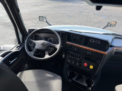 Cab interior of a 2021 International LT625 truck showing steering wheel, dashboard with gauges, center console, and wood trim.
