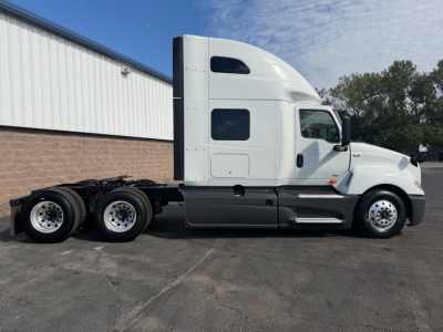 International LT625 tractor-trailer in side profile showing sleeper cab and dual rear axles with chrome fuel tanks and white paint.