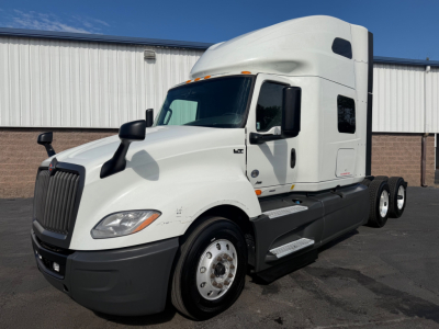 International LT625 sleeper tractor with white cab, black front bumper, and dual rear axles. Text visible on side include LT badge near door and grille area.