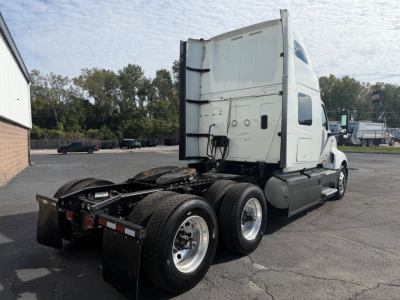 Truck tractor rear three-quarter view showing fifth wheel and dual rear axles with white sleeper cab.
