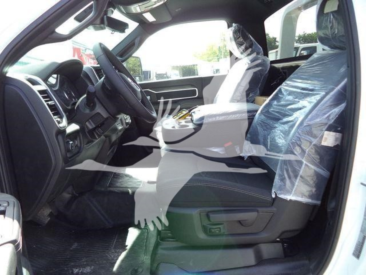 Ram 4500 interior view showing black cloth seats, steering wheel, center console, and front passenger seat with plastic cover; dashboard and door panel visible.