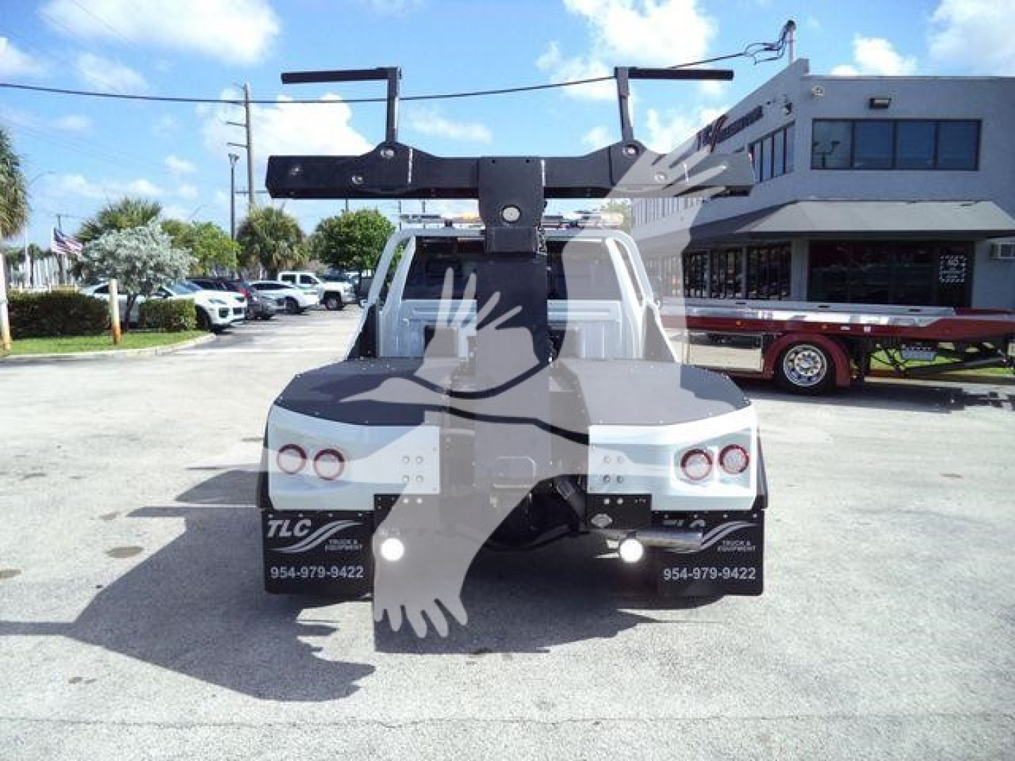 Truck bed with winch equipment mounted on the rear of a Ram 4500 utility truck, visible tail lights and license plate area, dealership contact numbers on bumper.