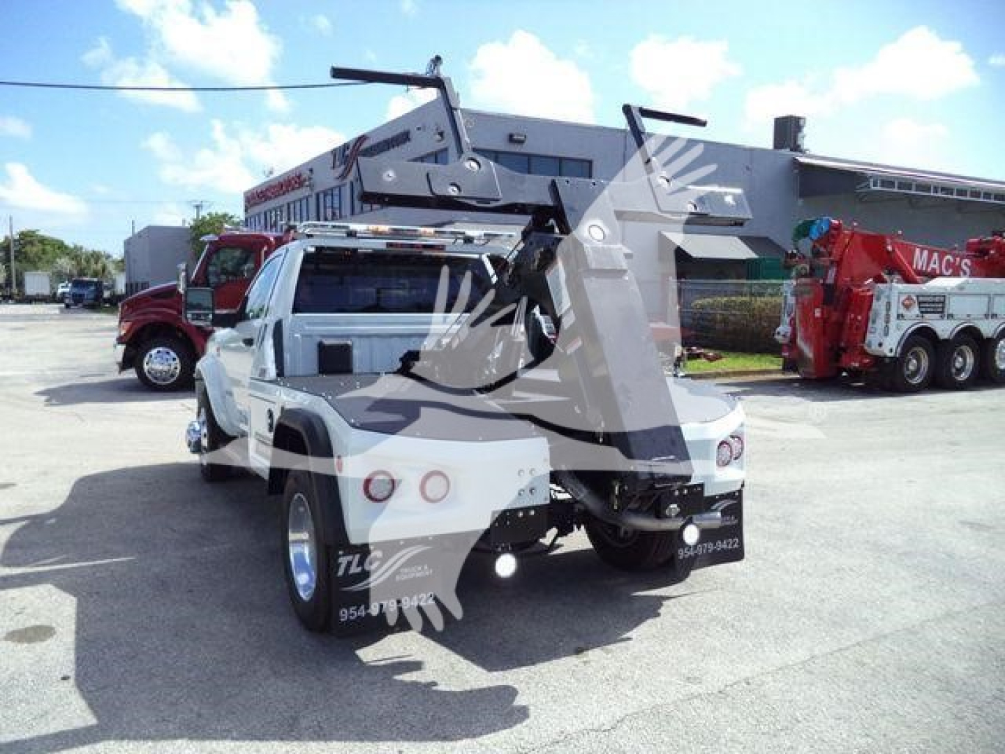 Ram 4500 winch truck rear view showing mounted winch and lifting apparatus with additional equipment in background.