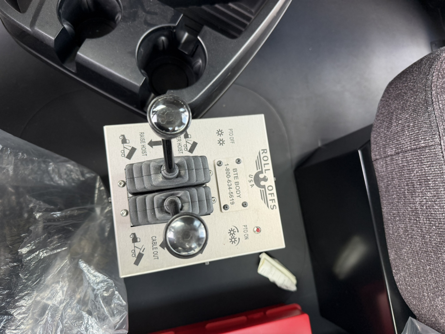 Rolloff truck cab interior showing gear selector panel with two joystick levers and labeled controls.