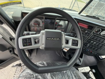 Wheel steering wheel and dashboard of a Mack GR64B truck cab with instrument cluster and controls visible.