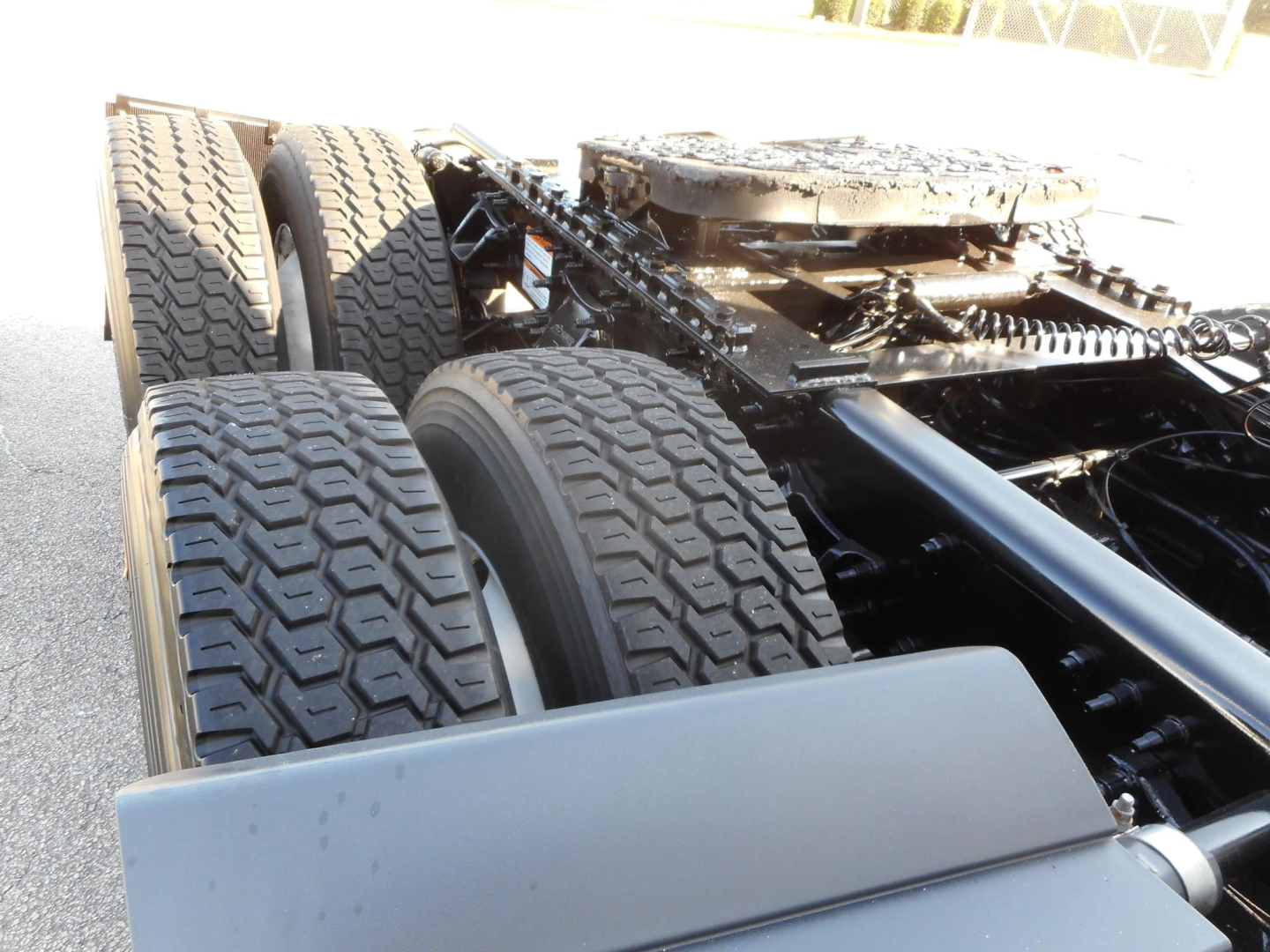 Freightliner Cascadia truck chassis showing dual rear axles and tires with heavy-duty suspension components.