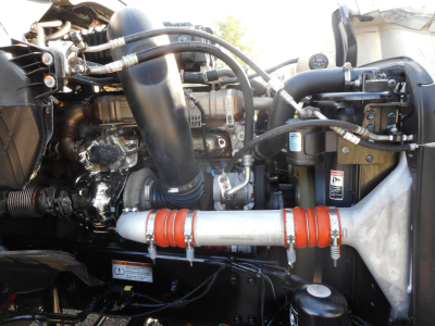 Freightliner Cascadia 126 engine bay showing turbo piping, hoses, and coolant/intercooler plumbing with red hose clamps.