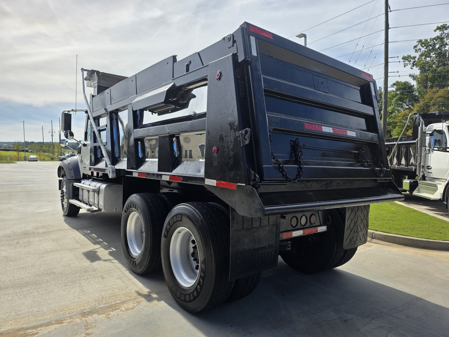 Dump truck rear view showing dump bed and dual rear axles with heavy-duty wheels and hydraulic lift on a Mack Granite chassis.