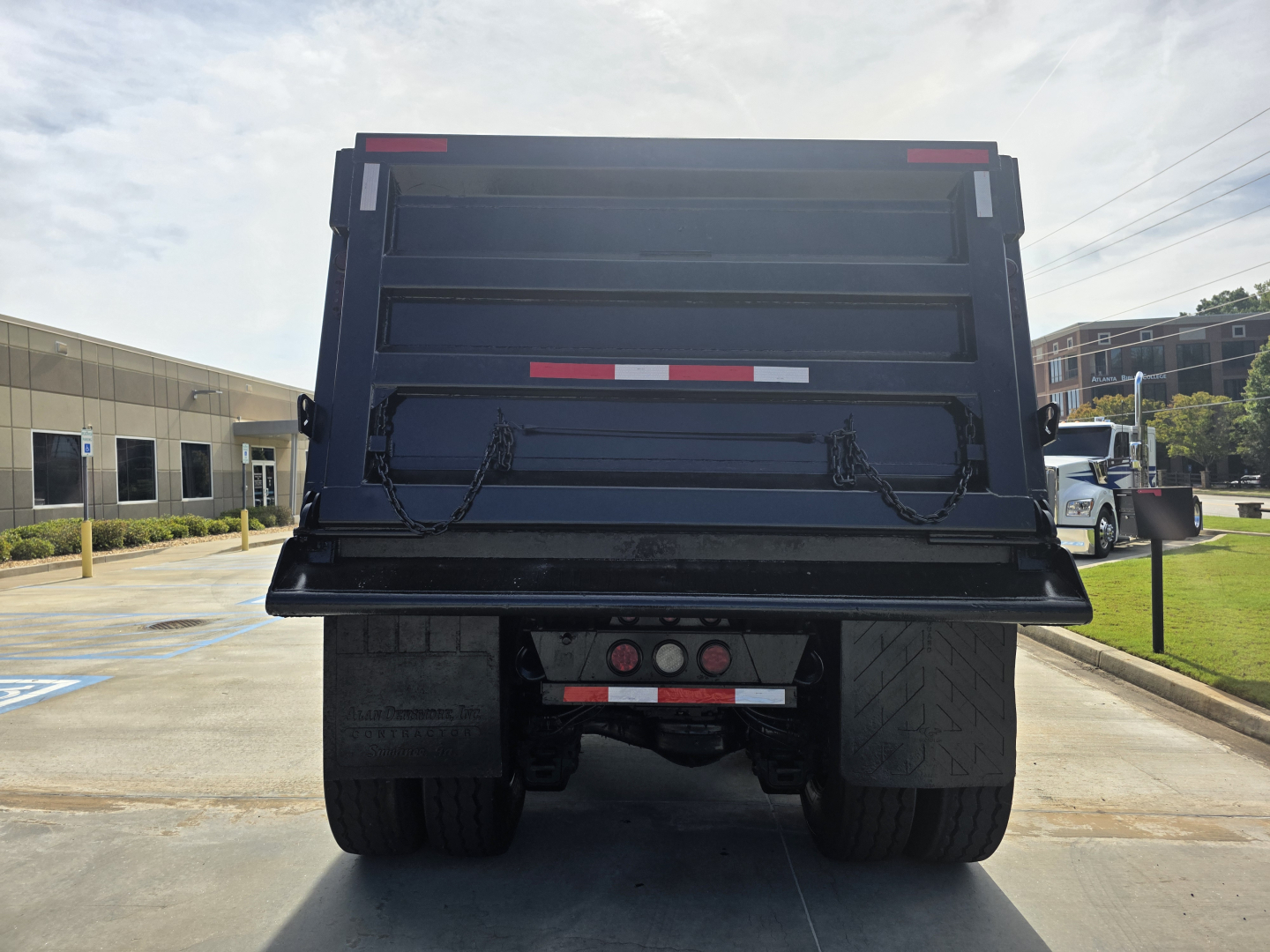 Rear view of dump truck bed on a 2022 Mack Granite showing taillights, bumper, chains, and reflective markings.