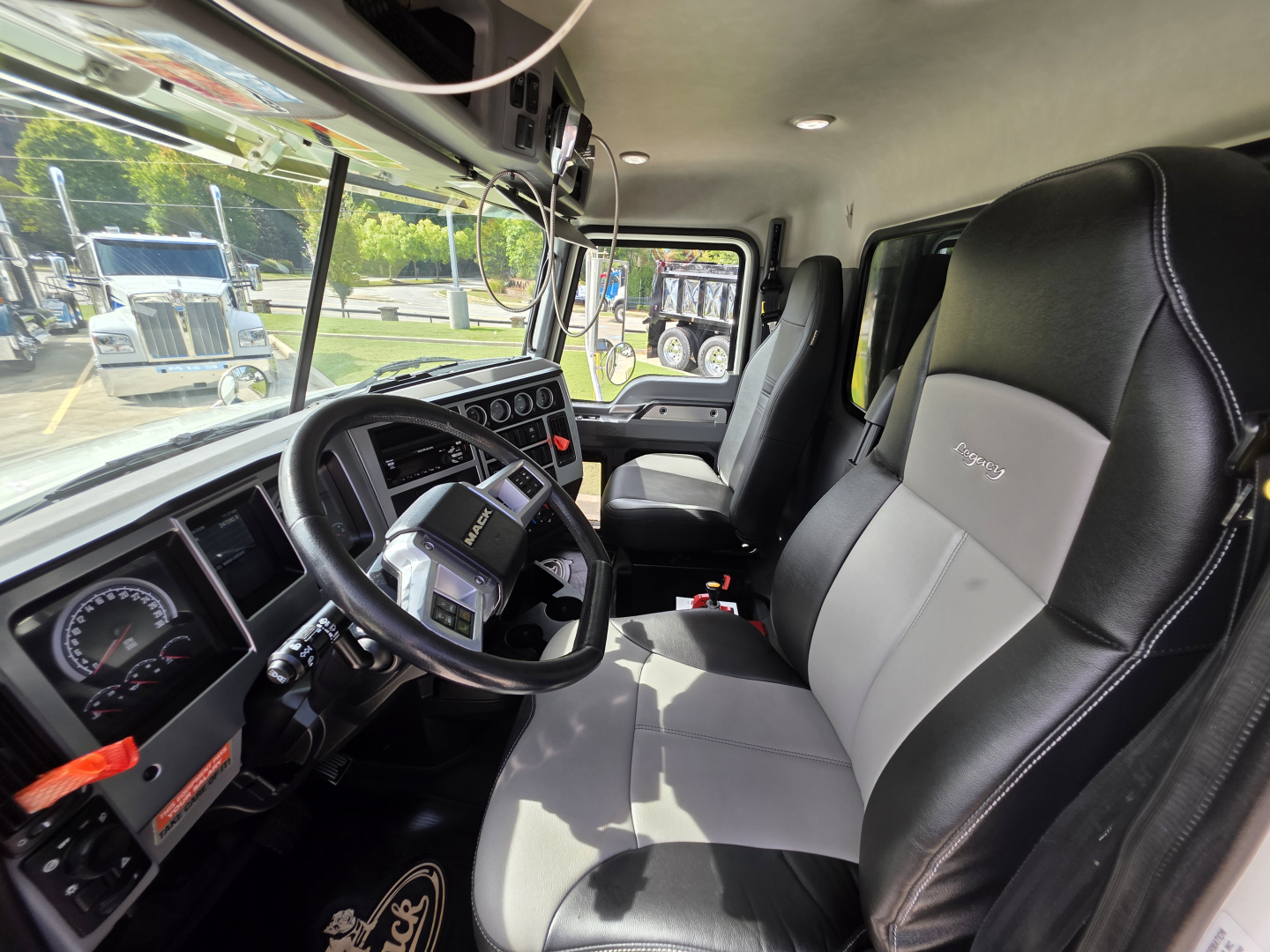 Mack Granite truck cab interior showing steering wheel dashboard and driver seat with gray and black upholstery.